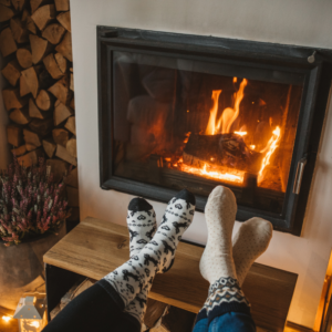 two feet in socks propped up in front of a fire in a fireplace