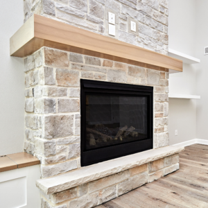 a gas fireplace surrounded by white brick masonry white a light wood mantel