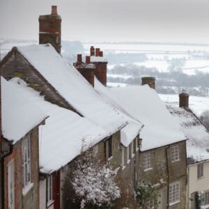 a row of houses with snowy roofs and chimneys