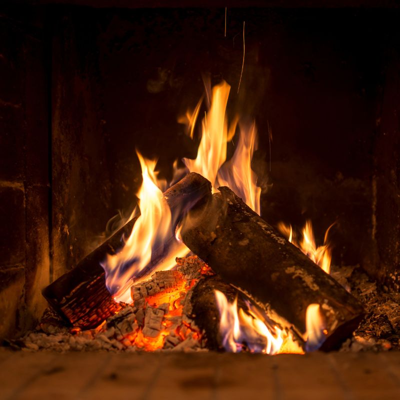 a pile of wood logs that are burning in a firebox