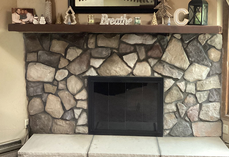 Photo of a fireplace after a total facelift, new cultured stone, hearth, and glass doors